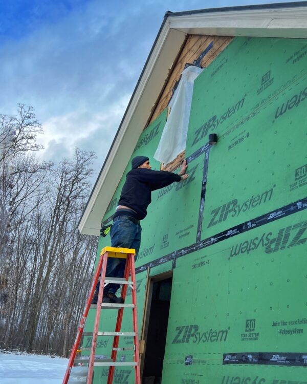 Tony tapes ZIP System panels on east elevation (Photo: R.P. Murphy)