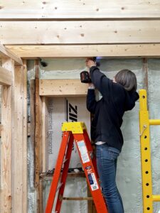 January 2023 Framing Flashback: Pam Installing Hurricane Hangers (Photo: Hroth Ottosen)